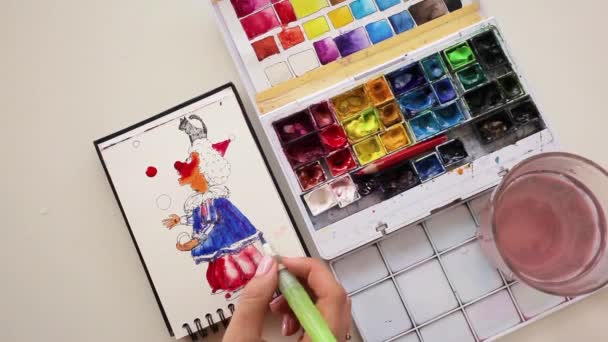 Een meisje tekening een jonglerende clown met groene pruik met behulp van aquarellen. — Stockvideo