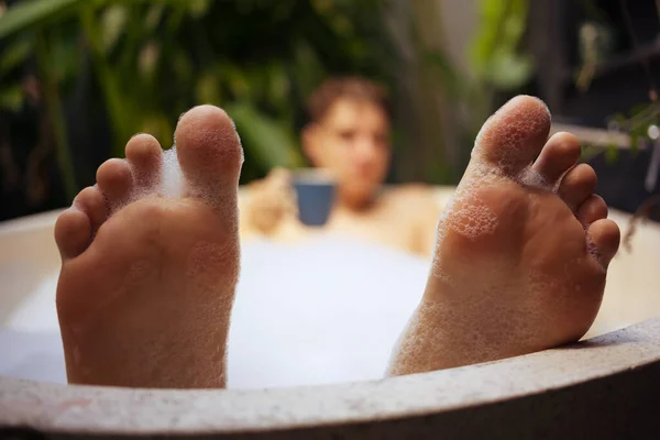 Funny male feet, defocused person drinking tea.