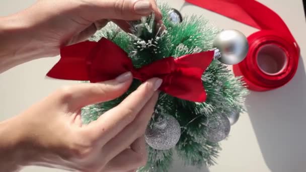 Chica poniendo lazo de seda roja en la parte superior del árbol de Navidad — Vídeos de Stock