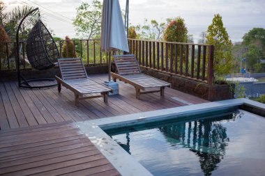 Akşam havuz kenarında. Yüzme havuzu güneşlikleri, ağaçlar