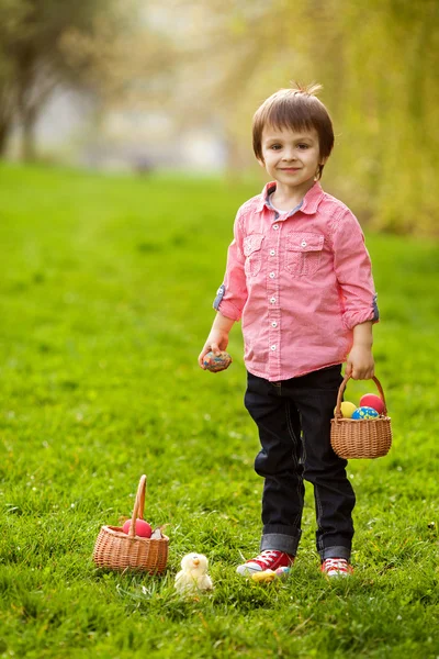 Adorabile ragazzo nel parco, si diverte con uova colorate per Easte — Foto Stock