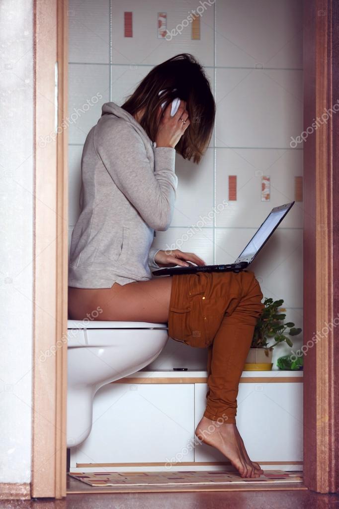 Young woman, working on computer in the toilet