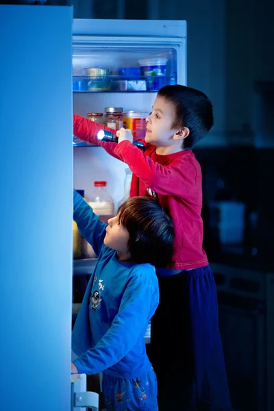 İki küçük çocuğu, gizlice tatlılar buzdolabından geceleri yemek — Stok fotoğraf