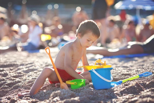 Mignon petit garçon d'âge préscolaire, jouer dans le sable sur la plage wi — Photo