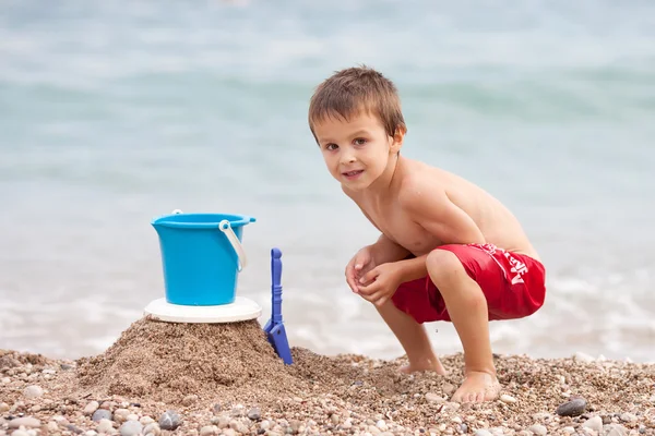 Mignon petit garçon d'âge préscolaire, jouer dans le sable sur la plage wi — Photo