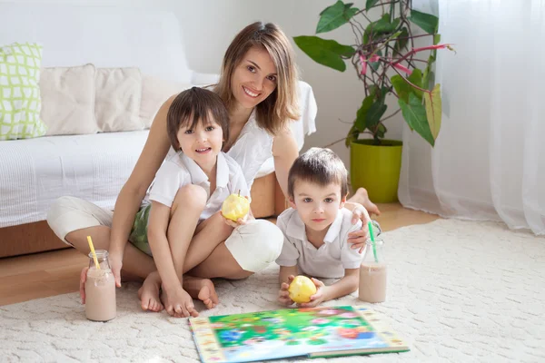 Young mother, read a book to her tho children, boys, in the livi — Stock Photo, Image