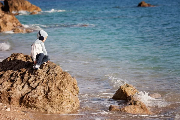 Dulce niño, sentado en una gran roca en el océano, contemplar — Foto de Stock