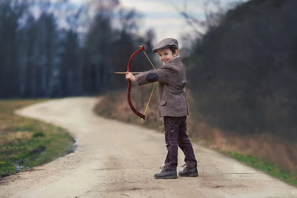 Чарівний маленький хлопчик дошкільного віку, стріляти з лука і стріли на смолоскипі — стокове фото