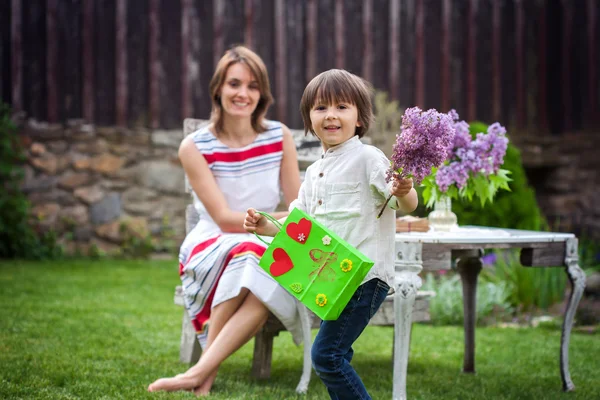 Beautiful mom, having coffee in a backyard, young cute child giv — Stock Photo, Image