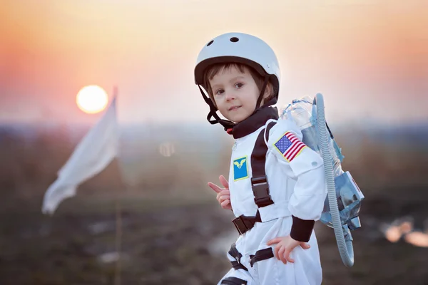 Un niño con un casco de astronauta y mirando hacia arriba.