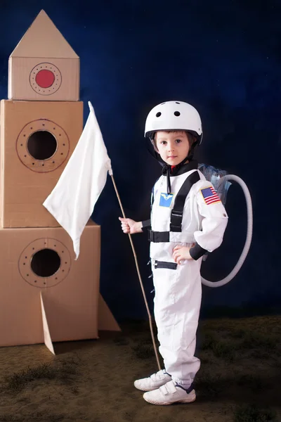 Schöner Vorschuljunge, als Astronaut verkleidet, mit Fahne und Auto — Stockfoto