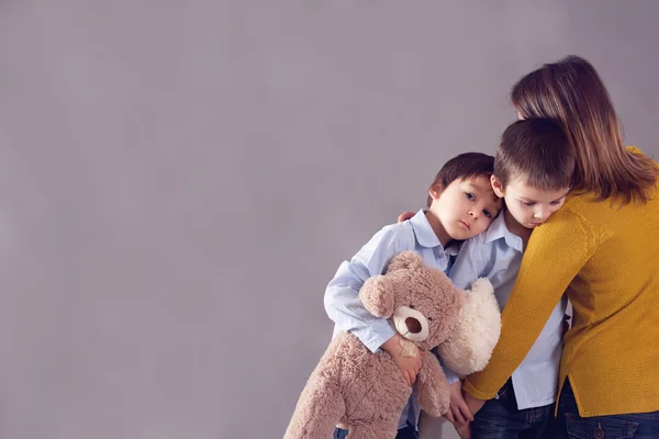 Sad little children, boys, hugging their mother at home, isolate — Stock Photo, Image