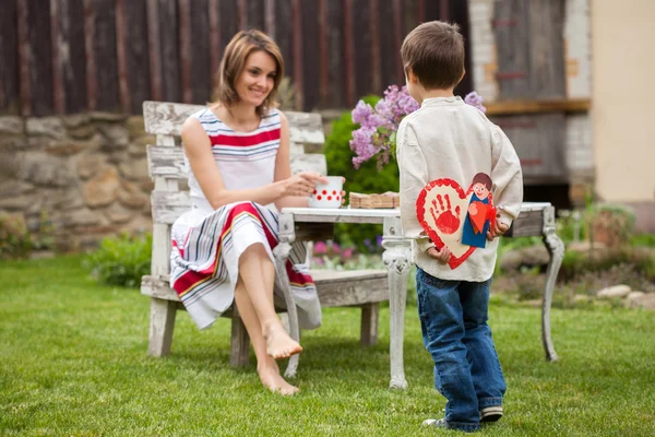 Beautiful mom, having coffee in a backyard, young cute child giv — Stock Photo, Image