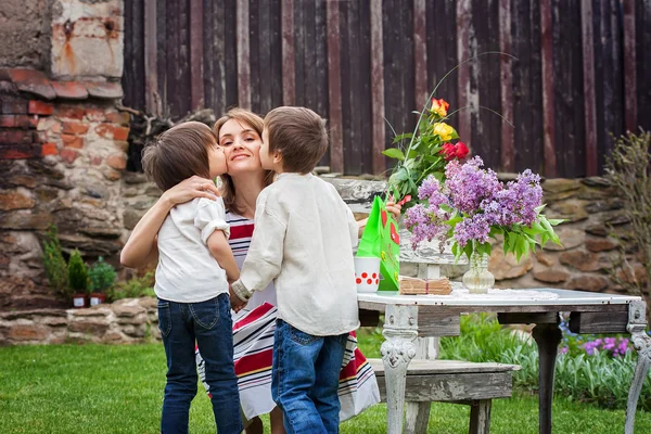 Beautiful mom, having coffee in a backyard, young cute child giv