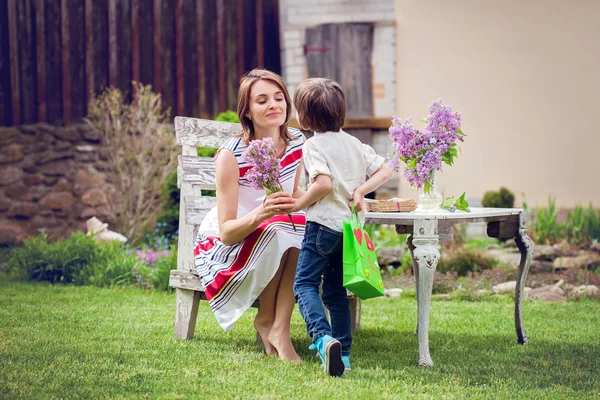 Beautiful mom, having coffee in a backyard, young cute child giv — Stock Photo, Image