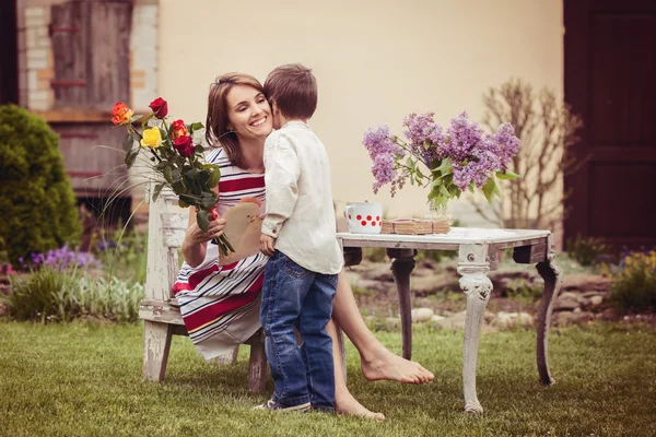 Beautiful mom, having coffee in a backyard, young cute child giv — Stock Photo, Image