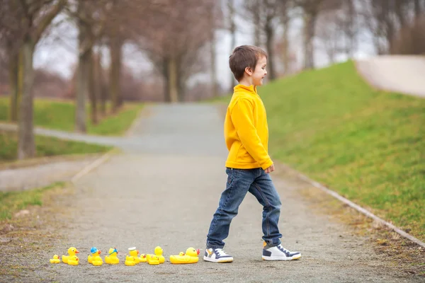 Adorable niño, niño, jugando en el parque con patos de goma, teniendo f — Foto de Stock