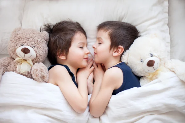 Dos chicos con osos de peluche, acostados en la cama, durmiendo por la tarde —  Fotos de Stock
