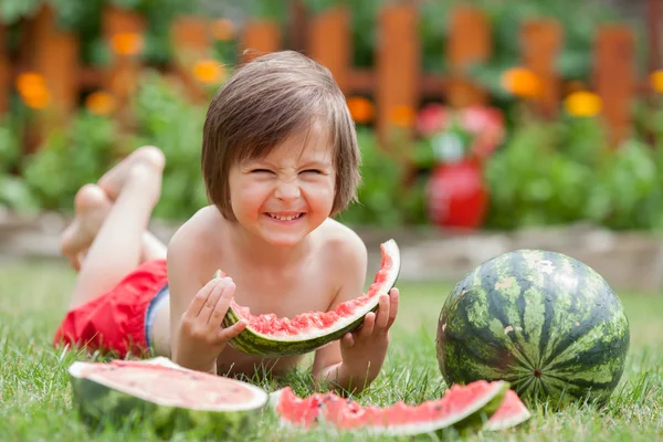 少年は、庭、夏にスイカを食べる — ストック写真