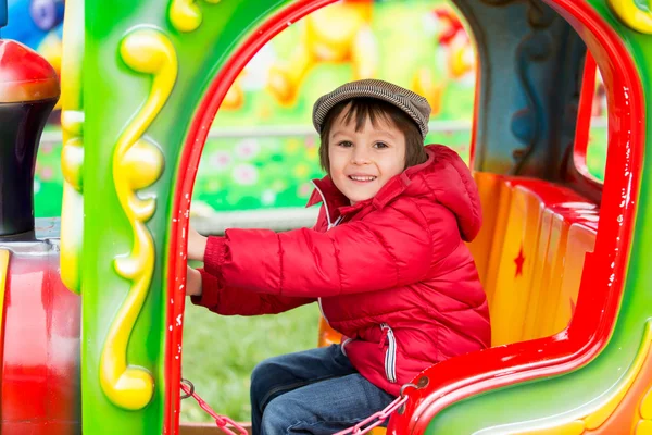 Beautiful boy having fun on the ride at the amusement park — Stock Photo, Image