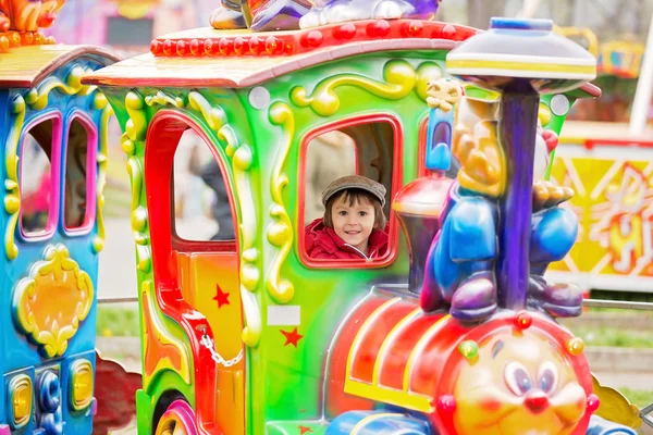 Beautiful boy having fun on the ride at the amusement park — Stock Photo, Image