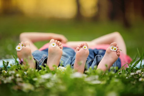 Niños felices, tumbados en la hierba, descalzos, margaritas —  Fotos de Stock