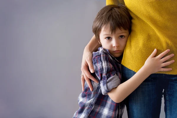 Copil trist, băiete, îmbrăţişându-şi mama acasă — Fotografie, imagine de stoc