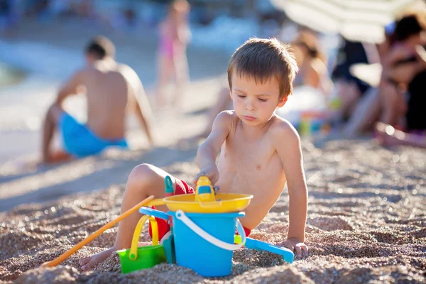 Mignon petit garçon d'âge préscolaire, jouer dans le sable sur la plage wi — Photo