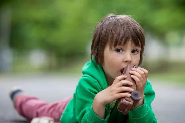 Grappige kleine jongen spelen met auto van chocolade, buiten — Stockfoto