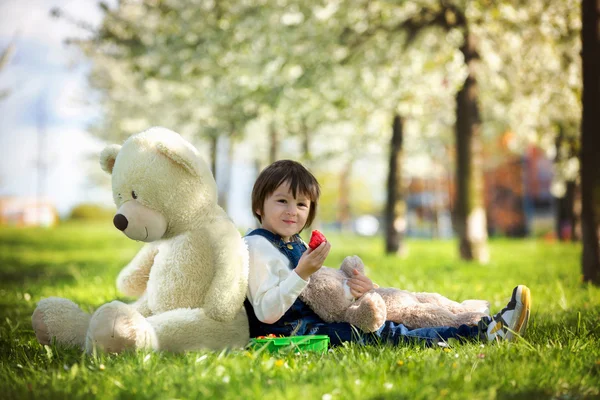 Niedlicher kleiner Junge, der an einem sonnigen Frühlingstag Erdbeeren im Park isst — Stockfoto