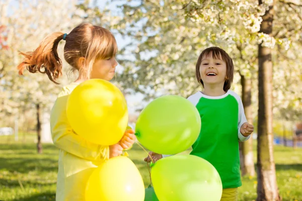 Carino bambina e ragazzo, amici, giocare con palloncini in un bl — Foto Stock