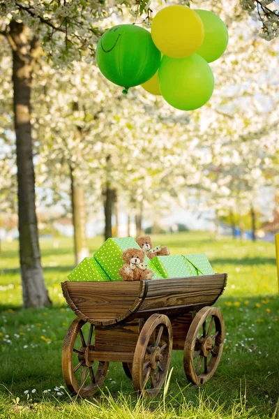 Chariot avec des cadeaux d'une fête d'anniversaire dans une pomme en fleurs — Photo