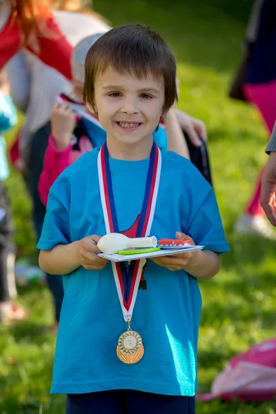 Dumny przedszkola chłopiec, trzymając nagrody i medale — Zdjęcie stockowe