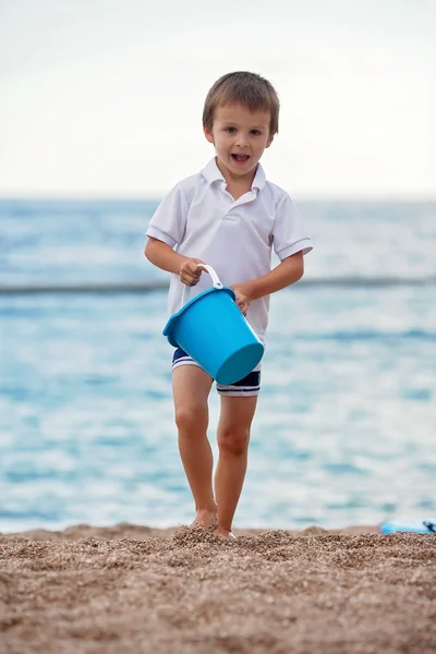 Mignon petit garçon d'âge préscolaire, jouer dans le sable sur la plage wi — Photo