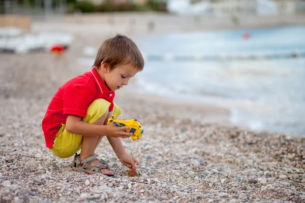 Garçon, jouer sur la plage le soir après la pluie avec des jouets — Photo