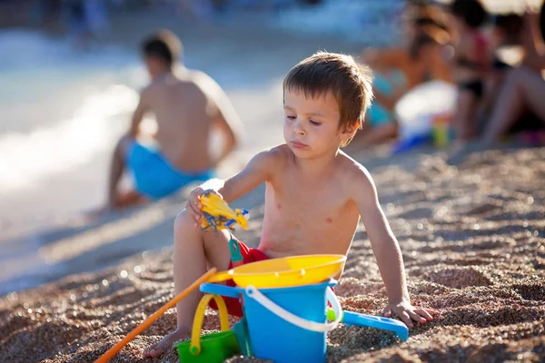 Ładny ładny chłopczyk, bawiące się w piasku na plaży wi — Zdjęcie stockowe