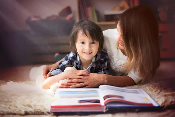 年轻的母亲，读了一本书给她的孩子，男孩在客厅里 o — 图库照片