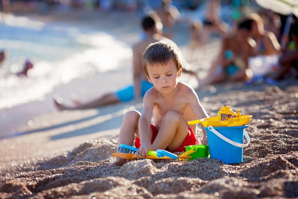 Cute little preschooler boy, playing in the sand on the beach wi — Stock Photo, Image