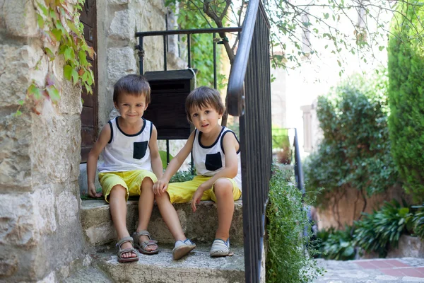 Two beautiful children, boy brothers, sitting on a stairs in fro — Stock Photo, Image