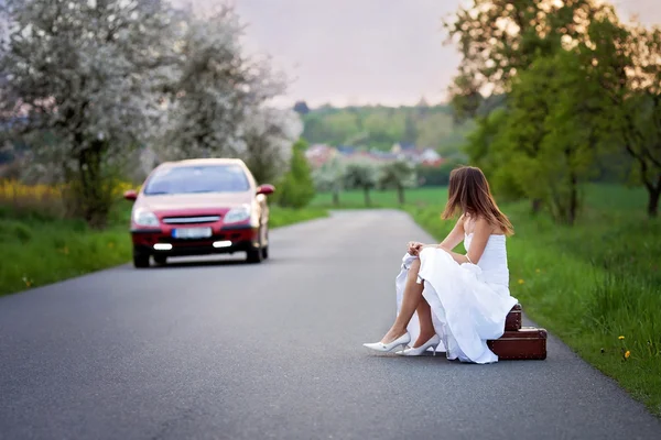 Молодая невеста на дороге с чемоданом — стоковое фото