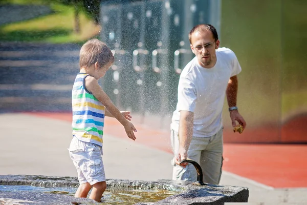 Padre e hijo, dulce niño, salpicando agua de una fuente —  Fotos de Stock