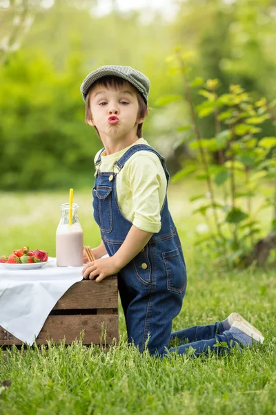 Niedliche schöne Kind, Junge, essen Erdbeeren und im Park — Stockfoto