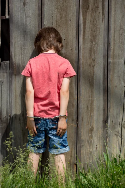 Schattige kleine jongen met de hand manchetten op zijn handen — Stockfoto