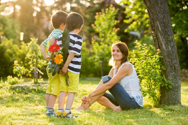 Young beautiful mother, sitting in a garden, little boys, her so — Stock Photo, Image