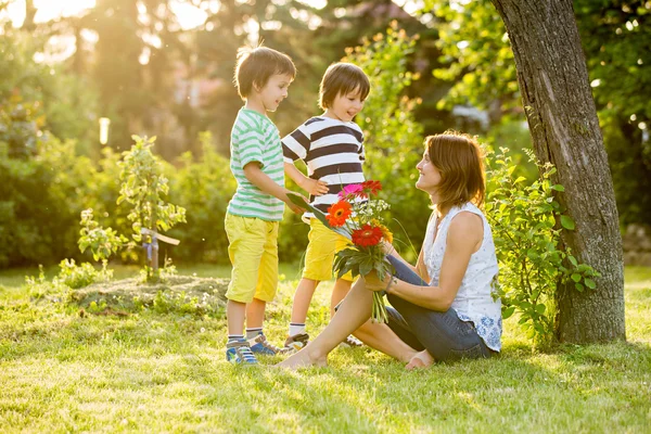 Jeune belle mère, assise dans un jardin, petits garçons, elle tellement — Photo