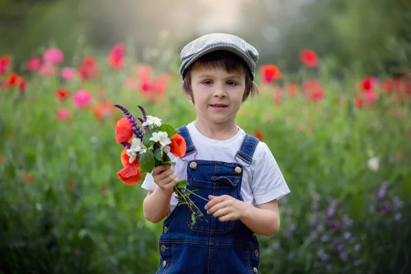 Милый дошкольный ребенок в маковом поле, держа букет дикой F — стоковое фото