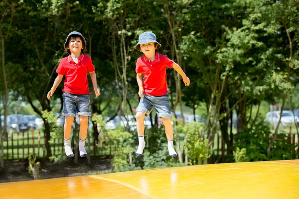Twee lieve kinderen, jongen broers, springen op een grote trampoline — Stockfoto