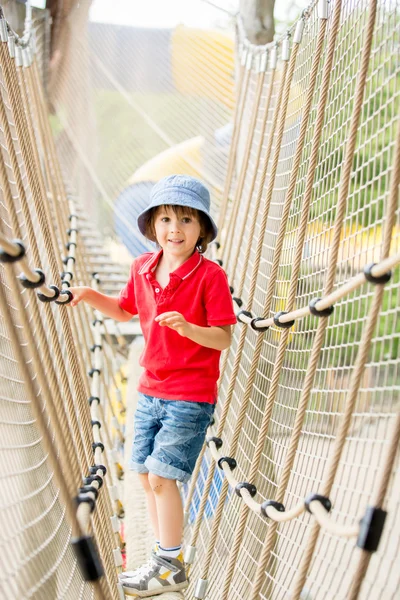 Bambino carino, ragazzo, arrampicata in una struttura di parco giochi corda — Foto Stock