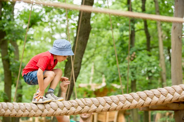 Söta barnet, pojke, klättring i en rep lekplats struktur — Stockfoto