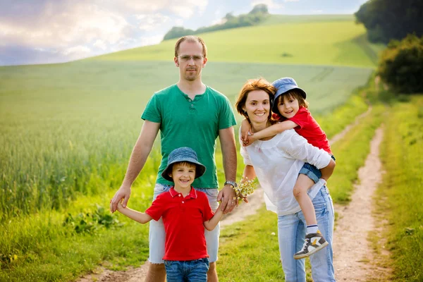 Familie van vier in veld op een landelijke weg, lente, plezier — Stockfoto